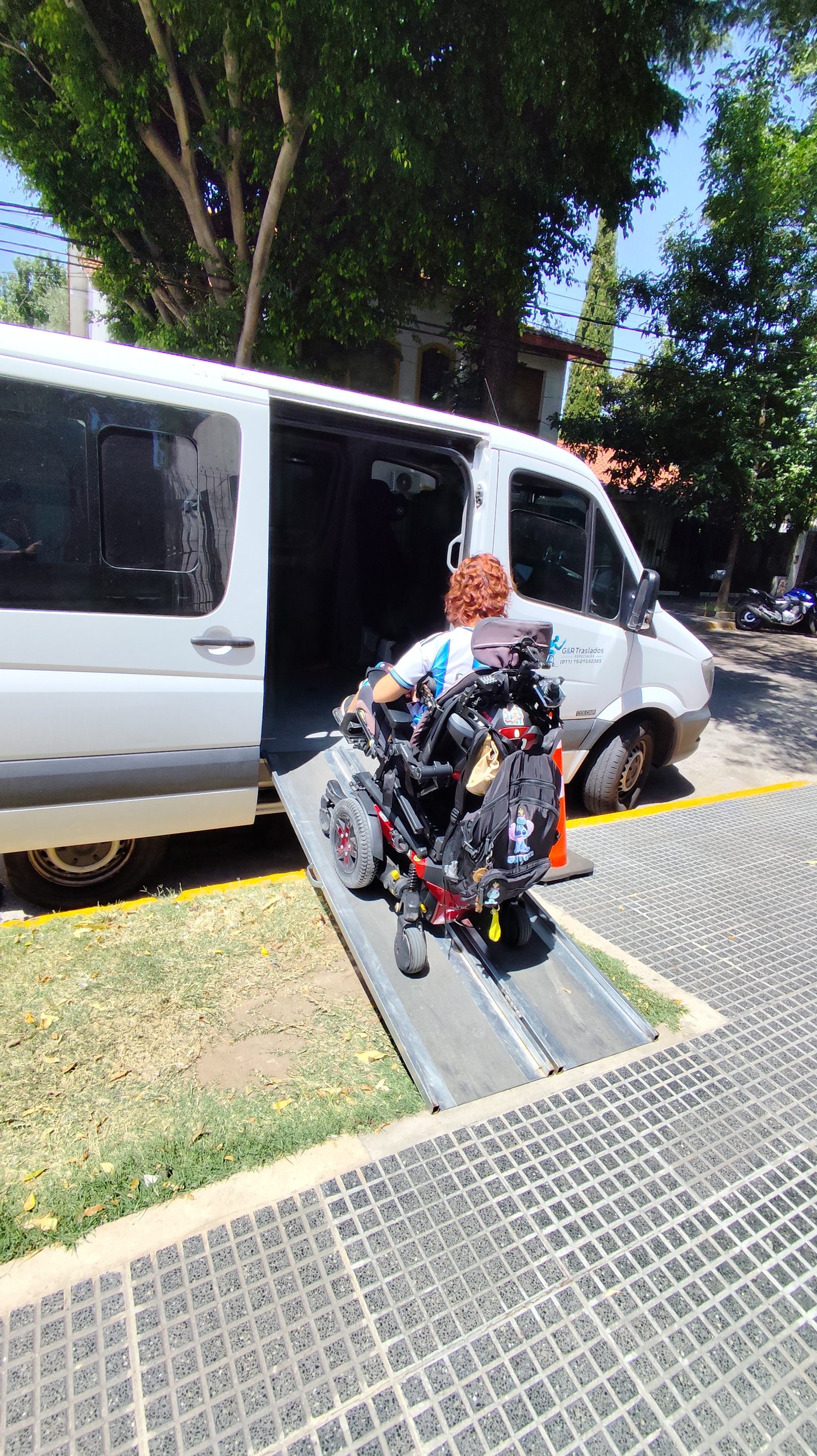 Persona en silla de ruedas motorizada subiendo por la rampa de la unidad